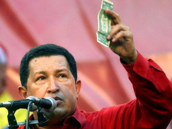 FILE - In this Jan. 23, 2005 photo, Venezuela's President Hugo Chavez holds up a U.S. dollar bill and challenges U.S. President George W. Bush to bet which of them will remain in power longer at a rally in Caracas, Venezuela. Venezuela's Vice President Nicolas Maduro announced that Chavez died on Tuesday, March 5, 2013, at age 58 after a nearly two-year bout with cancer. (AP Photo/Fernando Llano, File)