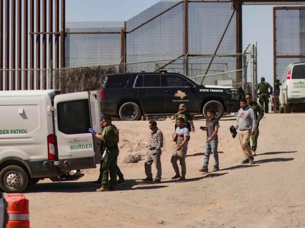 Migrantes detenidos son llevados por miembros de la Patrulla Fronteriza estadounidense a un vehículo, junto al muro fronterizo en El Paso, Texas (EE.UU).