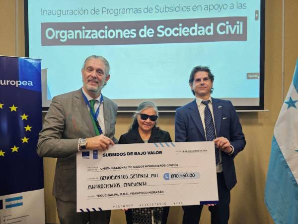 El representante de la Unión Europea, Mickael Roudaut y del PNUD, Iván Esquiva, al momento de hacer entrega del subsidio a la representante de la Unión Nacional de Ciegos de Honduras (UNCIH).