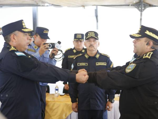 El comisionado David Leonardo Ortega Pagoaga (izquierda) recibe el bastón de mando del comisionado general Mario Molina Moncada, que lo acredita como nuevo director de la Dipampco.