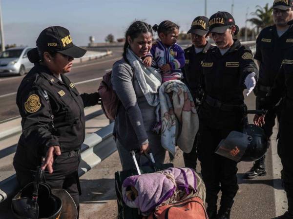 Policías hablan con migrantes en el paso fronterizo de control entre Santa Rosa (Perú) y Chacalluta (Chile).