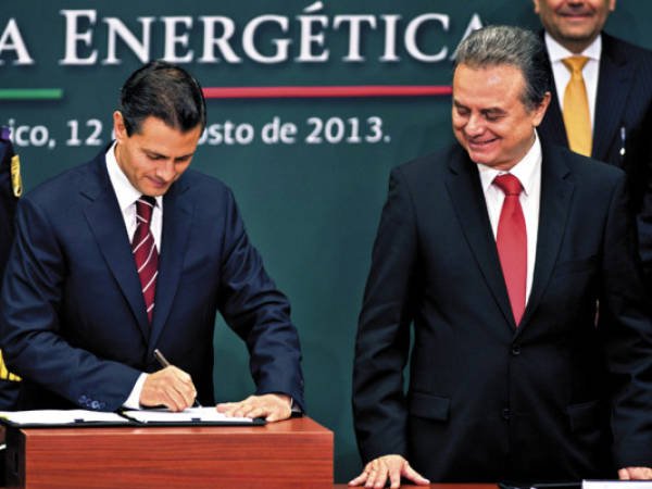 Mexican President Enrique Pena Nieto (L), next to Energy Secretary Pedro Joaquin Coldwell, signs the project of constitutional reform that would allow oil company Pemex to partner with private for exploration and extraction of hydrocarbons, keeping the company in the hands of the State, in Mexico City, on August 12, 2013. AFP PHOTO/RONALDO SCHEMIDT