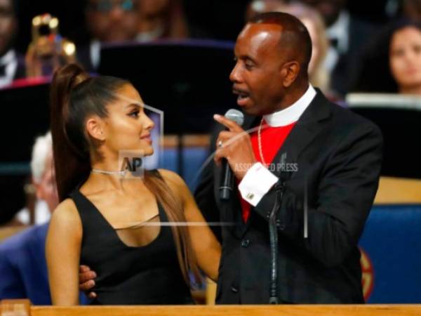 El obispo Charles H. Ellis, III (derecha) toma a la cantante Ariana Grande mientras habla durante el funeral en memoria de Aretha Franklin en el Templo Greater Grace de Detroit, el viernes 31 de agosto de 2018.