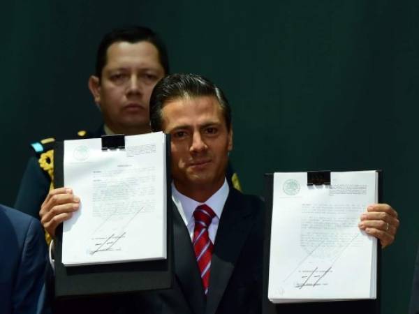 El presidente mexicano Enrique Peña Nieto muestra los documentos.