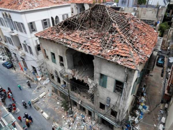 La gente pasa frente a una casa que resultó dañada durante la explosión de la semana pasada que golpeó el puerto marítimo de Beirut, Líbano. Foto AP.