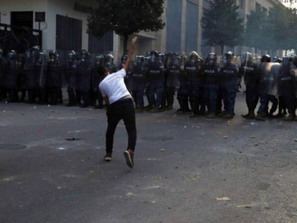 Un manifestante arroja rocas hacia policías antimotines durante una protesta tras la explosión del 4 de agosto en Beirut, Líbano. Foto AP.