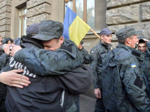 TOPSHOTSUkraine's National Guard Soldiers embrace each other during a protest next to the President administration building in Kiev on October 13, 2014. Hundreds of Ukrainian conscripts of former interior troops left their barracks and protested outside Ukraine?s President Petro Poroshenko administration building to demand their demobilization due to the expiration of their military service term. AFP PHOTO/GENYA SAVILOIV