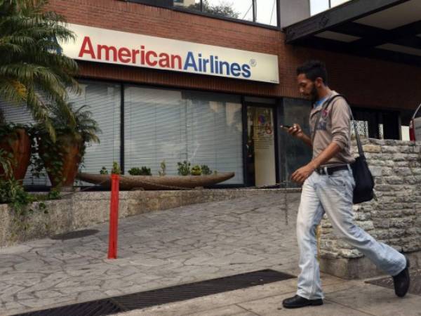 Una persona camina por una oficina de venta de boletos de American Airlines que está cerrada.