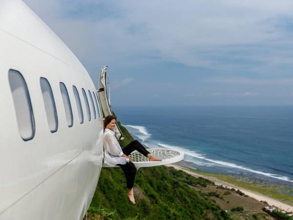 El avión de pasajeros está situado al borde de un acantilado, asomando inquietantemente una de sus alas sobre el abismo a 150 metros sobre el nivel del océano. Un huésped observando del paisaje marino desde el avión.