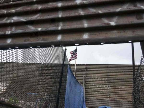 Una bandera nacional de EE. UU. Cuelga de la valla fronteriza entre Estados Unidos y México en Tijuana, Baja California. Agencia AFP.