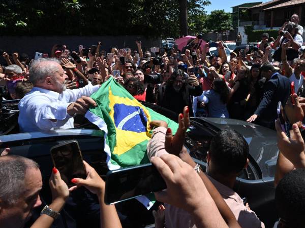 El expresidente brasileño (2003-2010) y candidato del izquierdista Partido de los Trabajadores (PT), Luiz Inacio Lula da Silva, despliega una bandera brasileña al salir del colegio electoral durante la segunda vuelta de las elecciones presidenciales.