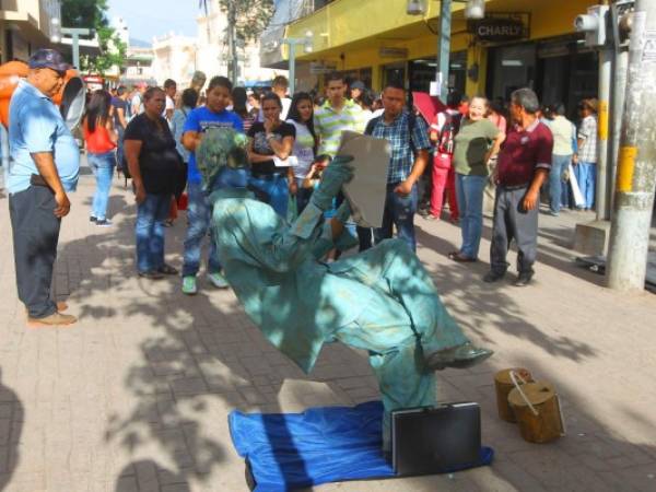 En la peatonal cerca de la plaza central, un joven simula a un ejecutivo leyendo un periódico donde personas observan y se entretienen con la creatividad de este joven. Fotografía / Johny Magallanes