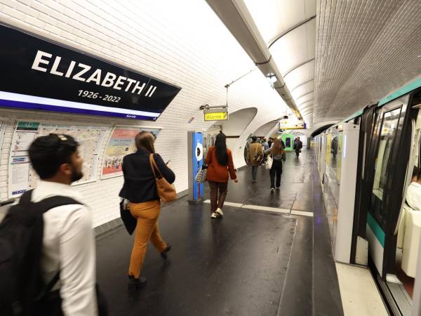 Los viajeros pasan junto a un letrero en la estación de metro parisina “George V”, que se reemplaza temporalmente con un cartel que dice “Elizabeth II 1926-2022”.