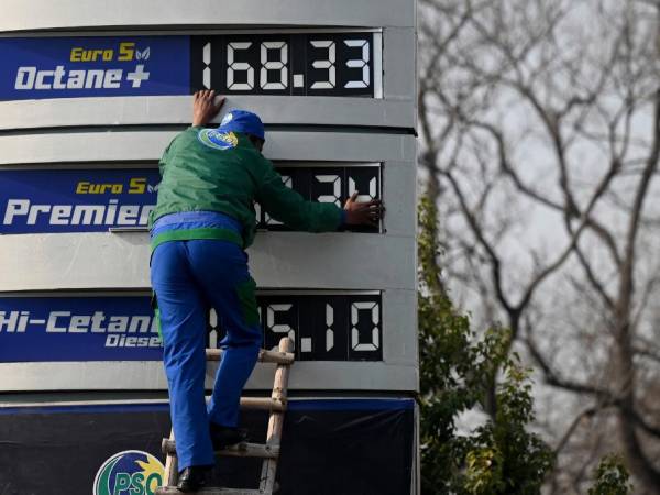 Un empleado de una gasolinera actualiza la última lista de precios de combustible después de un aumento en los precios de los productos derivados del petróleo.