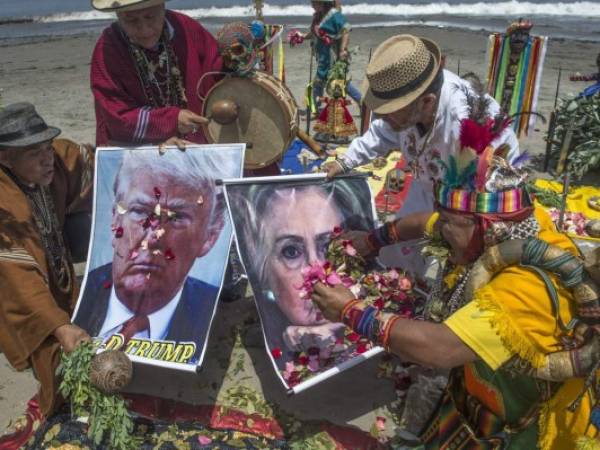 Son siete chamanes y una chamana que lanzan pétalos de flores y escriben 'EEUU' con granos de maíz sobre un trozo de tela. Foto: AFP