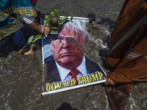 Los Chamanes sumergen en el agua la foto de Trump, lo llenan de arena y el chaman Mejía se lanza encima de él en una maniobra que se asemeja a un 'tackle' de rugby. Foto: AFP