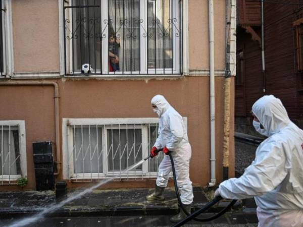 Members of the Fatih Municipality disinfects and wash down a street in the Zeyrek district in Istanbul to prevent the spread of the novel coronavirus, COVID-19, on March 20, 2020. - The religious affairs authority, Diyanet, ordered the closure of around 90,000 mosques in Turkey on March 20, the day of particularly important prayers in the Muslim faith. (Photo by Ozan KOSE / AFP)