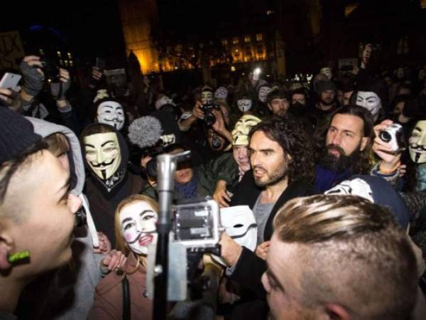 El comediante británico Russell Brand (C) se une a los manifestantes anti-capitalistas durante los 'millones de máscaras de marzo'