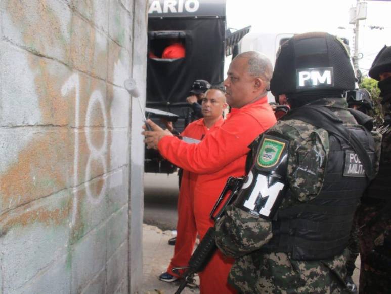 De overol naranja y grilletes, reclusos borran “placazos” de maras y pandillas en la capital