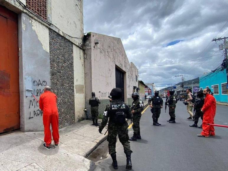 De overol naranja y grilletes, reclusos borran “placazos” de maras y pandillas en la capital