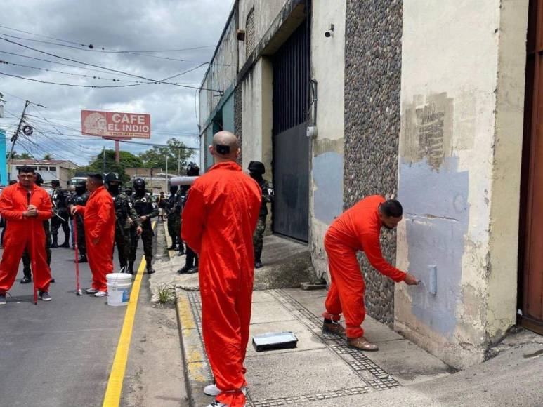 De overol naranja y grilletes, reclusos borran “placazos” de maras y pandillas en la capital