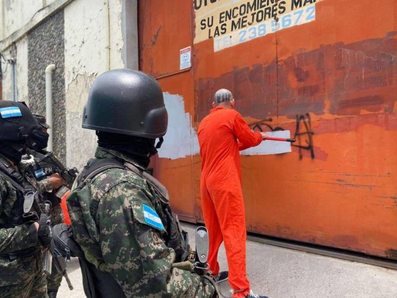 De overol naranja y grilletes, reclusos borran “placazos” de maras y pandillas en la capital