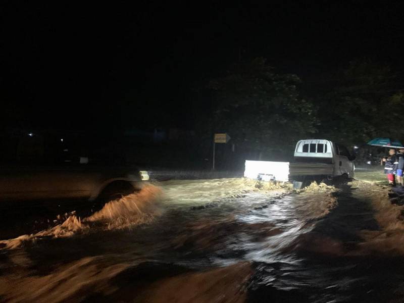 Vehículos livianos atraviesan con precaución la carretera inundada en Olanchito, una de las zonas más afectadas esta noche a causa de la tormenta tropical Sara.