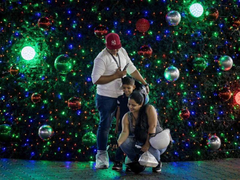 Personas se toman una fotografía junto a un árbol navideño este lunes, en Caracas.