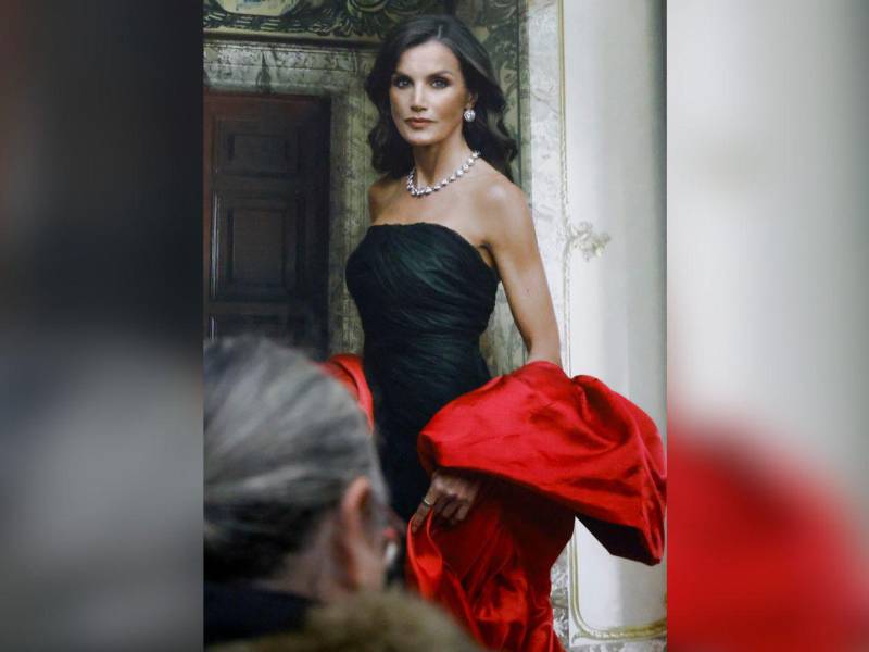 La reina Letizia luce en el retrato un vestido con escote palabra de honor de tul y una capa de gala en seda, ambos diseño del español Cristóbal Balenciaga.