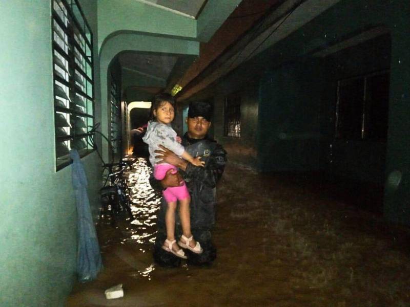 Un miembro de las Fuerzas Armadas carga a una niña en brazos luego de las inundaciones en el sector de Villa Neen, en La Ceiba, Atlántida.