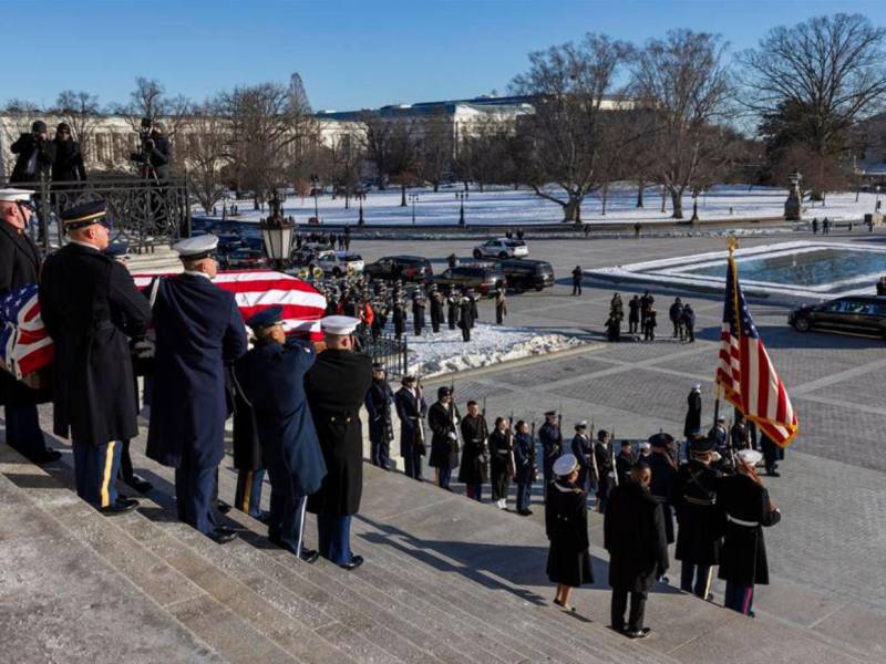 Cubierto con la bandera, el ataúd del expresidente estadounidense Jimmy Carter es transportado por un equipo conjunto de portadores de féretros fuera del Capitolio Estados Unidos en Washington.