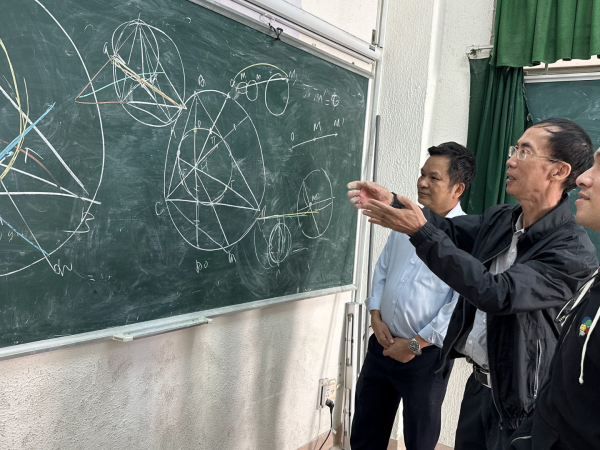 Thang Luong (der.) escudriña un problema de geometría con dos de sus antiguos profesores en Ho Chi Minh, Vietnam.