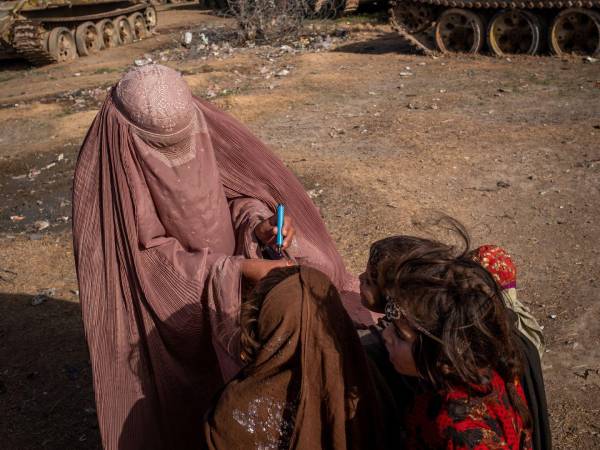 Trabajadora de salud en Kandahar, Afganistán marca el dedo de una niña para mostrar que recibió la vacuna contra la polio.