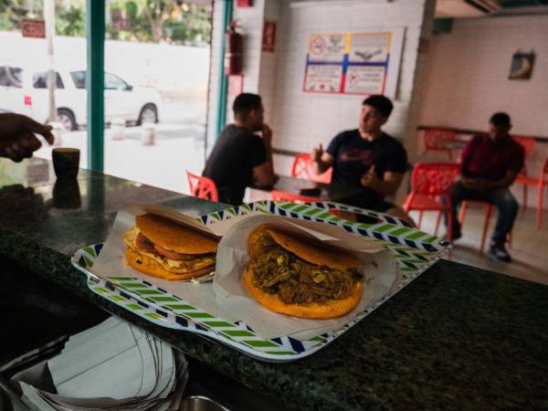 Para venezolanos, arepas son toda una comida. Dos rellenas de carne y ensalada caprese en Caracas, Venezuela.