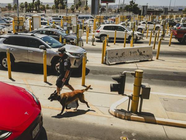 Funcionarios fronterizos de Estados Unidos revisan autos en el cruce de San Ysidro en California. (Meridith Kohut para The New York Times)