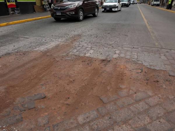 Los conductores de carros y de motocicletas deben esquivar los enormes agujeros de la calle.