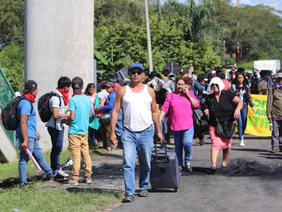 Con maleta en mano y niños en brazos, hondureños caminan por protesta en carretera CA-5