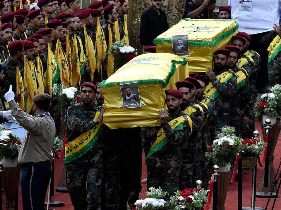 Combatientes de Hezbolá llevan los ataúdes de cuatro personas que murieron un día antes en explosiones de beepers, durante una procesión fúnebre en el suburbio sur de Beirut, Líbano.